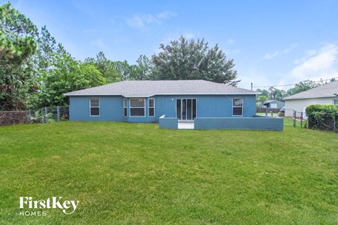 a blue house with a grassy yard and a fence