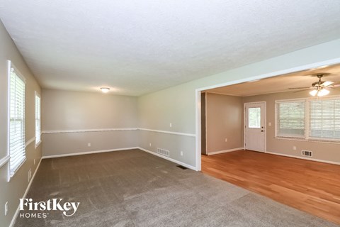 the living room and dining room of a house with wood flooring and white walls