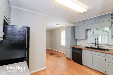 a kitchen with white cabinets and a black refrigerator