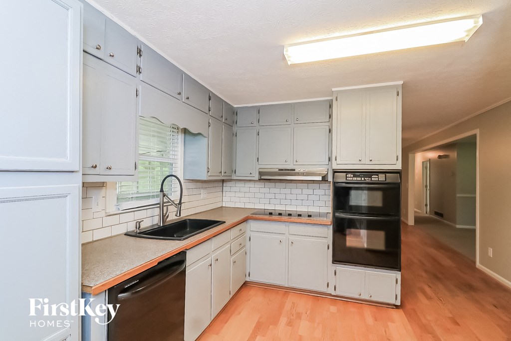 a kitchen with white cabinets and a sink and a stove