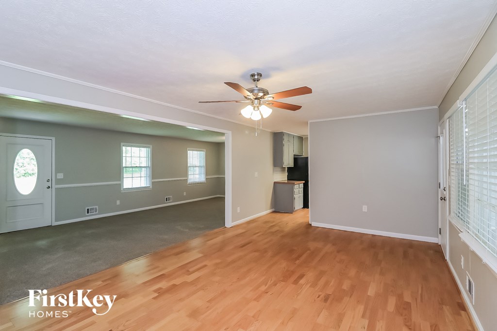 the living room and dining room with wood flooring and a ceiling fan