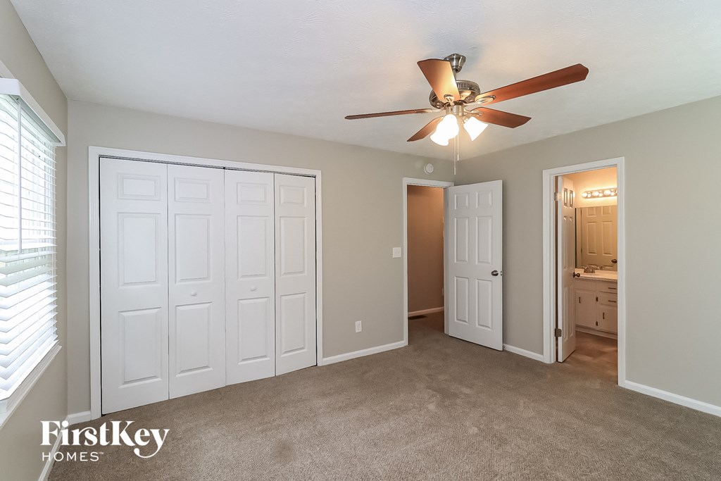 a bedroom with a ceiling fan and a door to a bathroom