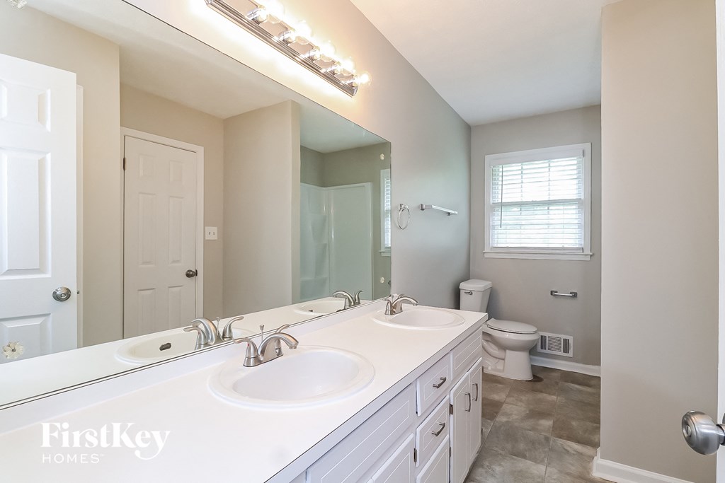 a bathroom with two sinks and a toilet and a large mirror