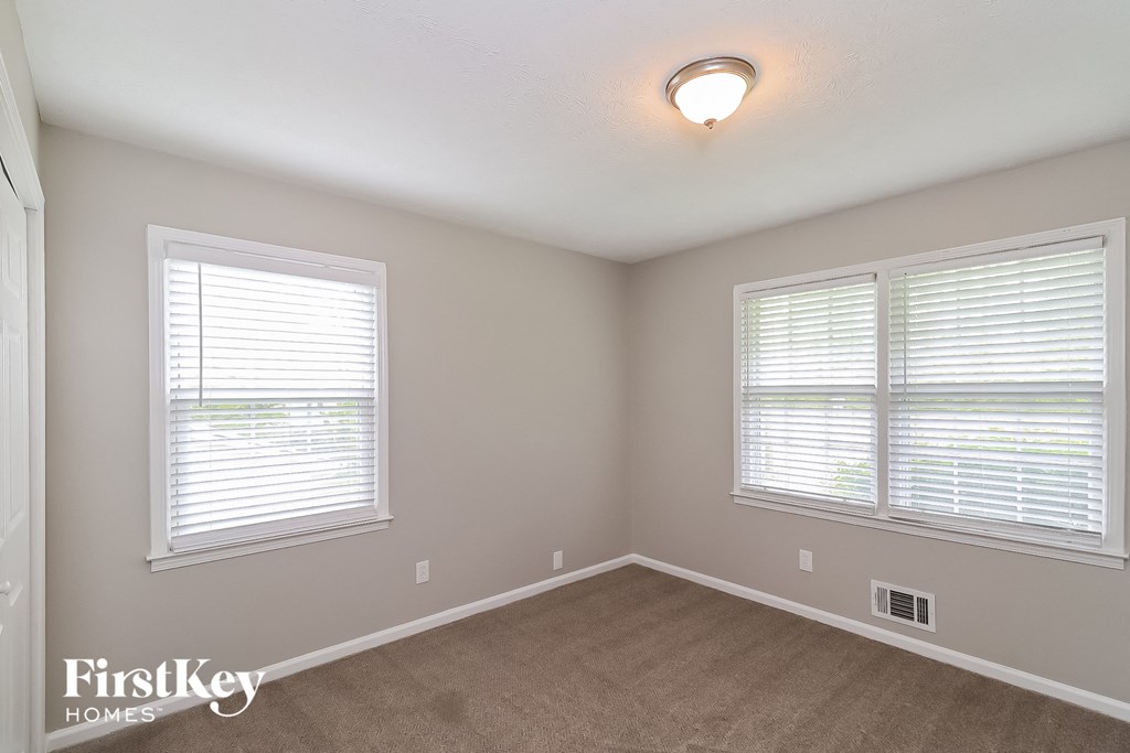 a bedroom with two windows and a carpeted floor