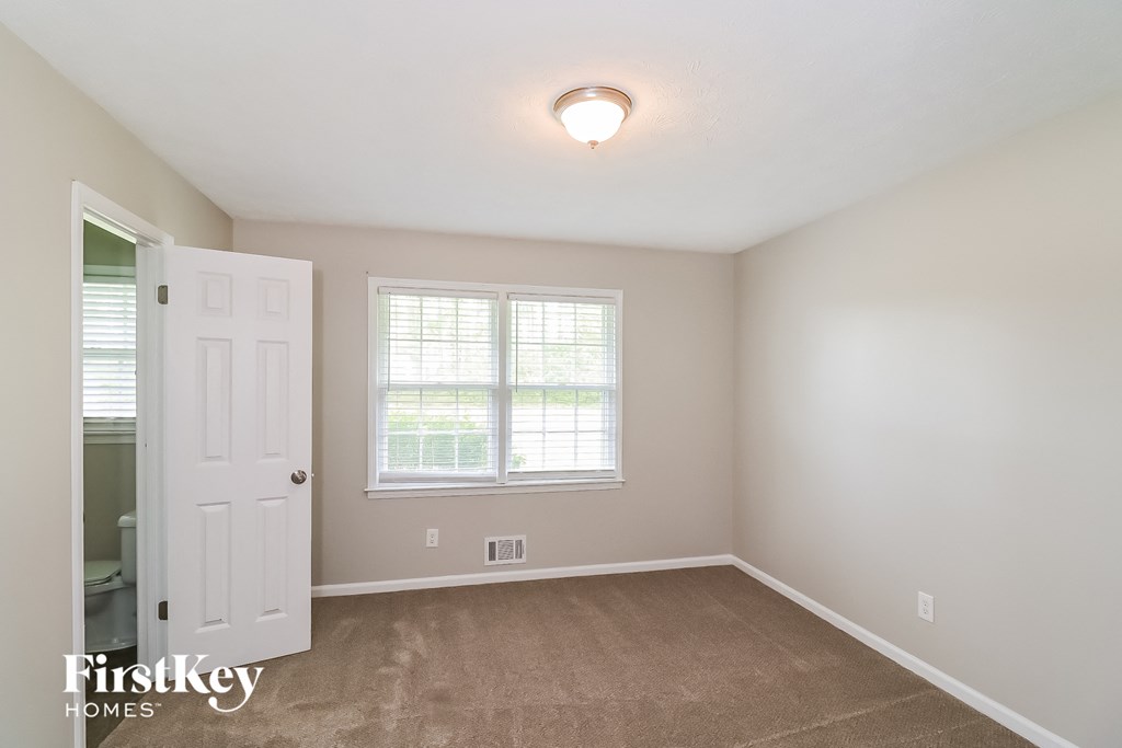a bedroom with a carpeted floor and a white door and window