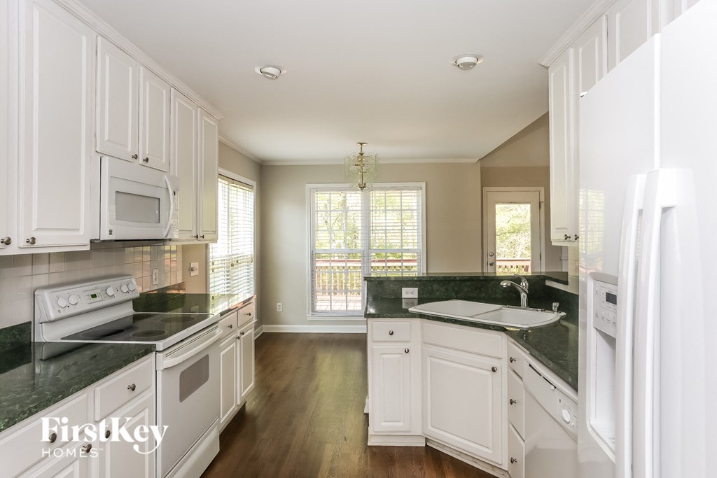 A kitchen with white cabinets and a black countertop.