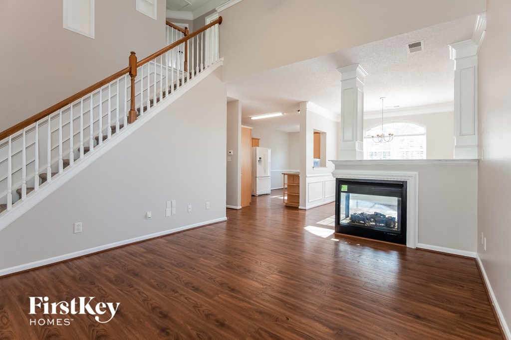 an empty living room with a fireplace and a staircase