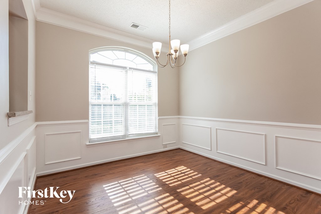 an empty dining room with a large window and wooden floors
