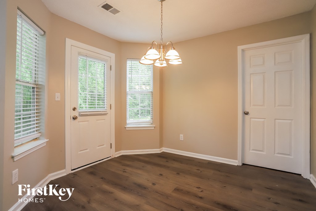 an empty dining room with a white door and a chandelier
