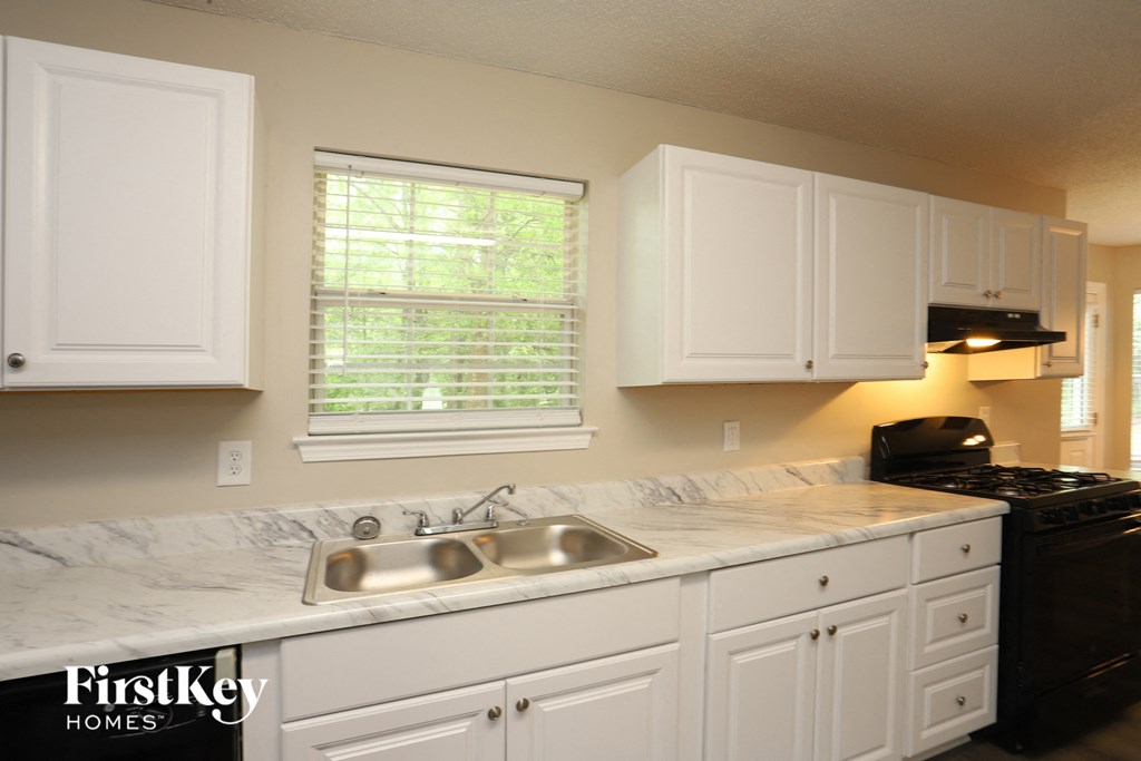 a kitchen with white cabinets and a sink and a window