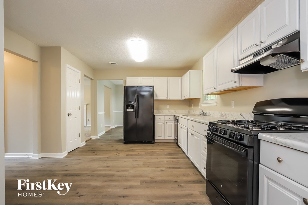 an empty kitchen with white cabinets and black appliances