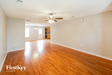 A spacious room with wooden floors and a ceiling fan.