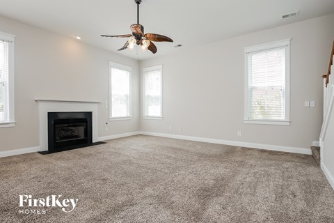 a clean living room with a fireplace and a ceiling fan