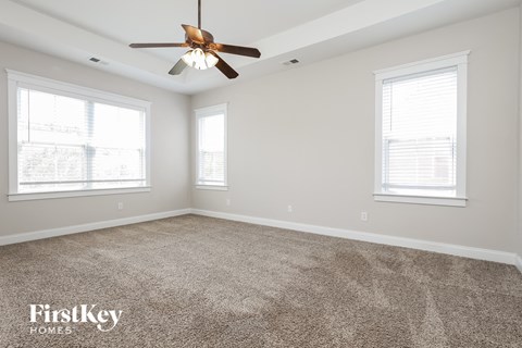 an empty room with a ceiling fan and two windows