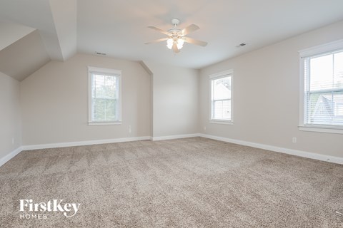 an empty room with a ceiling fan and two windows