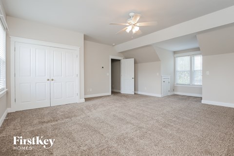 a spacious living room with carpet and a ceiling fan