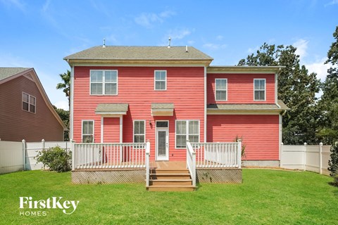 a red house with a deck and a white fence