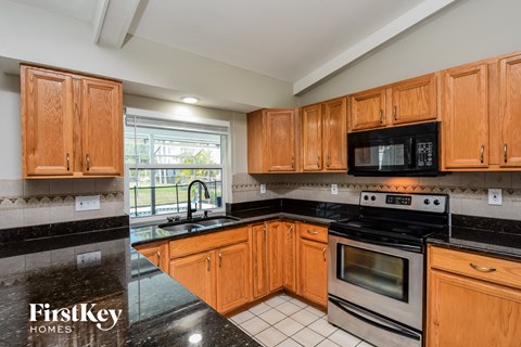 full view of the kitchen with wood cabinets and black countertops and stainless steel appliances
