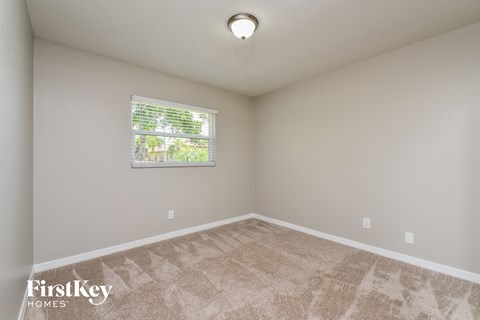a spacious living room with carpet and a window