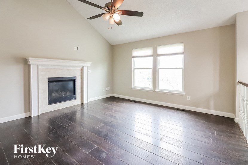 an empty living room with a fireplace and a ceiling fan