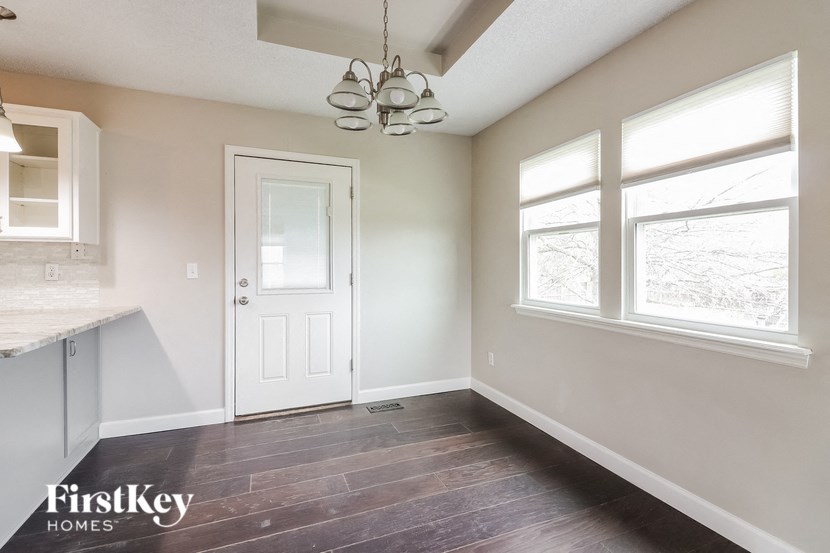 an empty kitchen with a white door and three windows