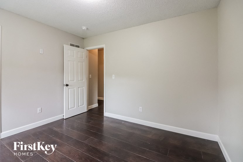 a bedroom with white walls and wood floors and a white door