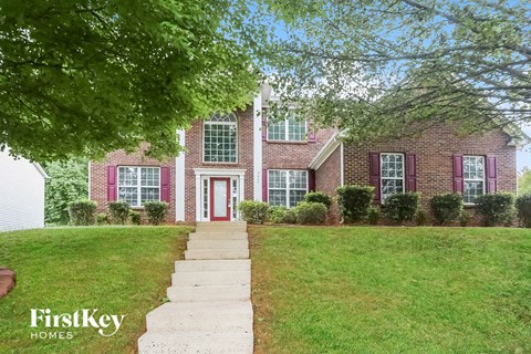 a brick house with red shutters and a lawn in front of it