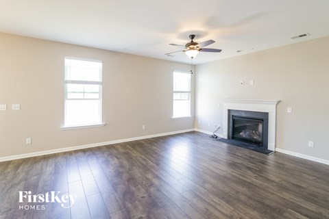 A spacious living room with a fireplace and a ceiling fan.