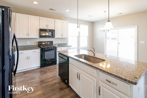 A kitchen with a black fridge and a granite counter top.