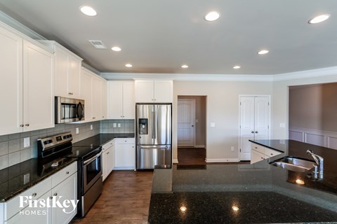 A kitchen with white cabinets and a black countertop.