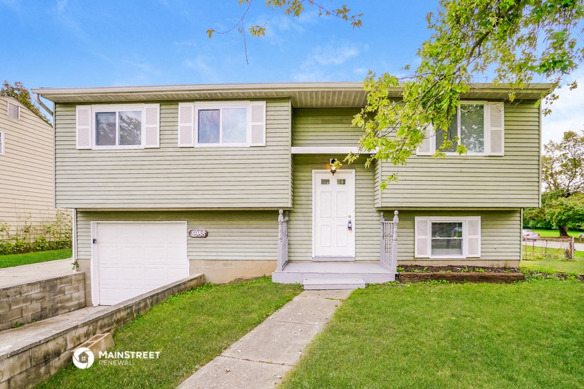 a green and white house with two garage doors and a sidewalk