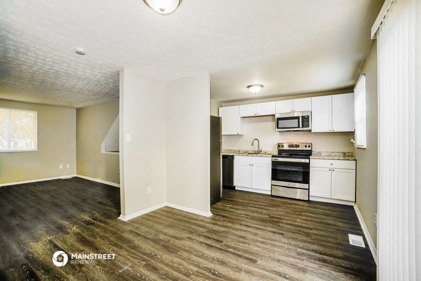 an empty kitchen with a wood floor and white cabinets