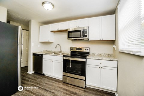 a kitchen with white cabinets and black appliances and a refrigerator