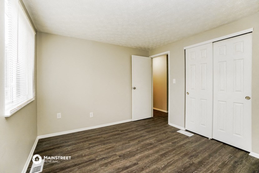 the living room of an apartment with wood flooring and white doors