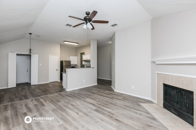 an empty living room with a fireplace and a ceiling fan