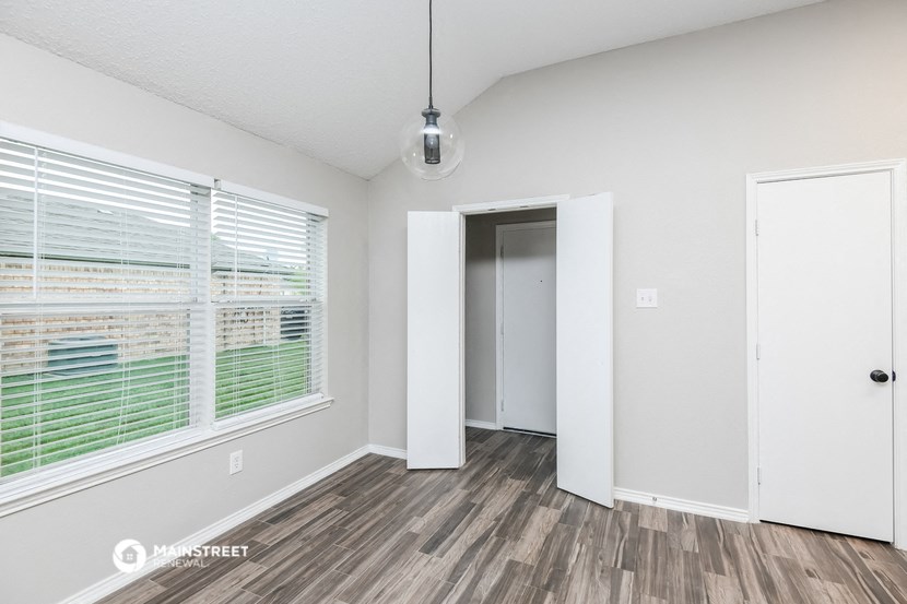 the spacious living room with large window and wood flooring