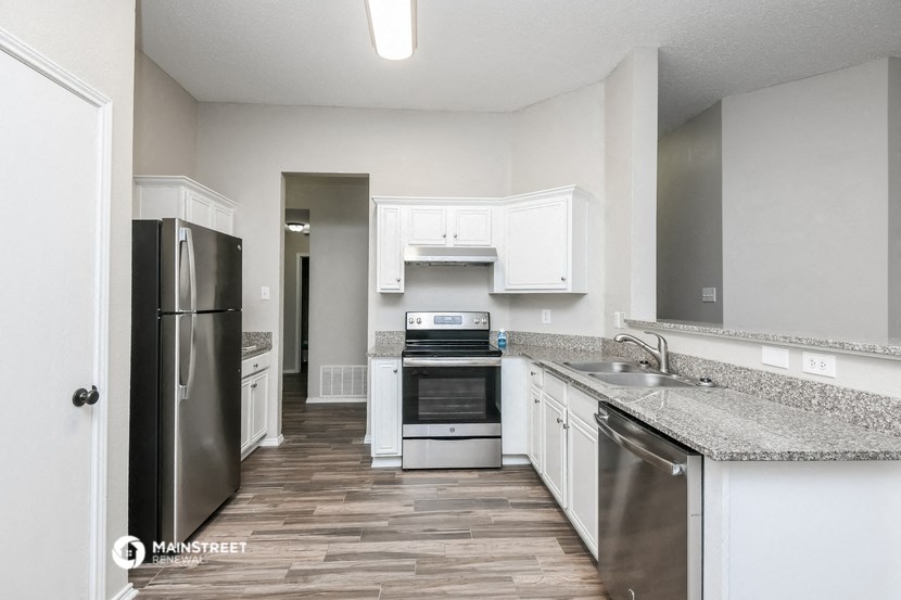 an empty kitchen with white cabinets and stainless steel appliances