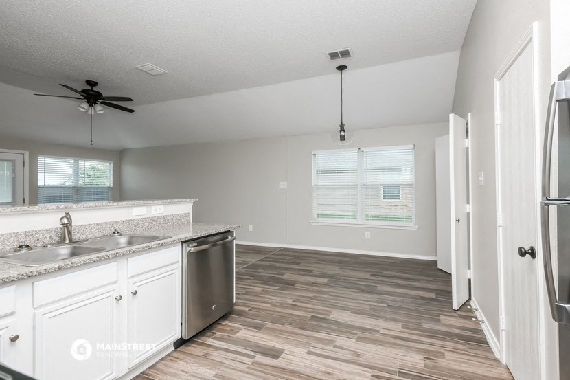an empty kitchen and living room with a refrigerator and a sink