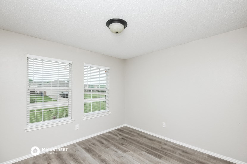 the spacious living room with two windows and wood flooring