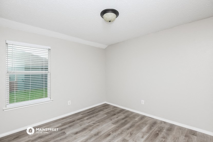 the spacious living room of a manufactured home with wood flooring and a window