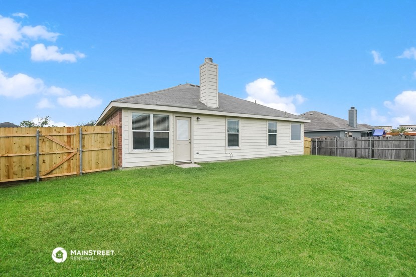 a backyard with a white house and a wooden fence