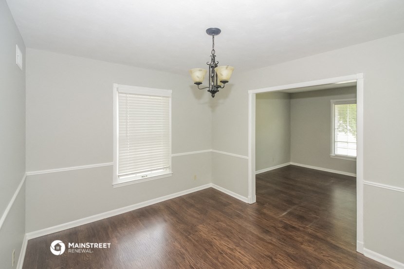 the living room of a renovated house with wood flooring and a chandelier