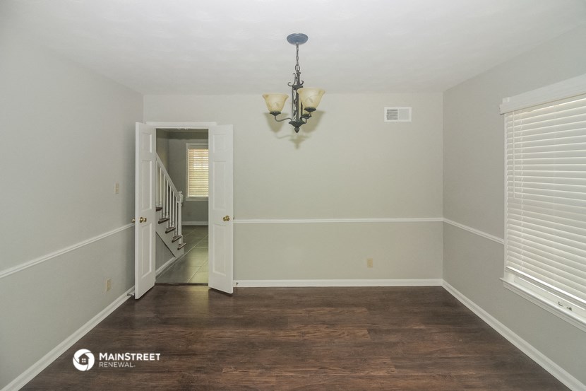 an empty room with a hard wood floor and a chandelier