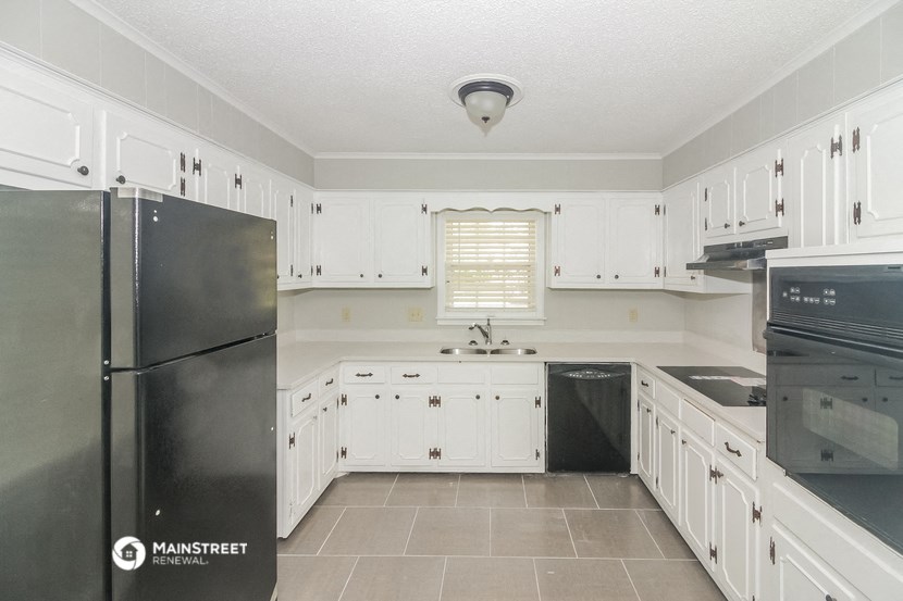 a white kitchen with black appliances and white cabinets