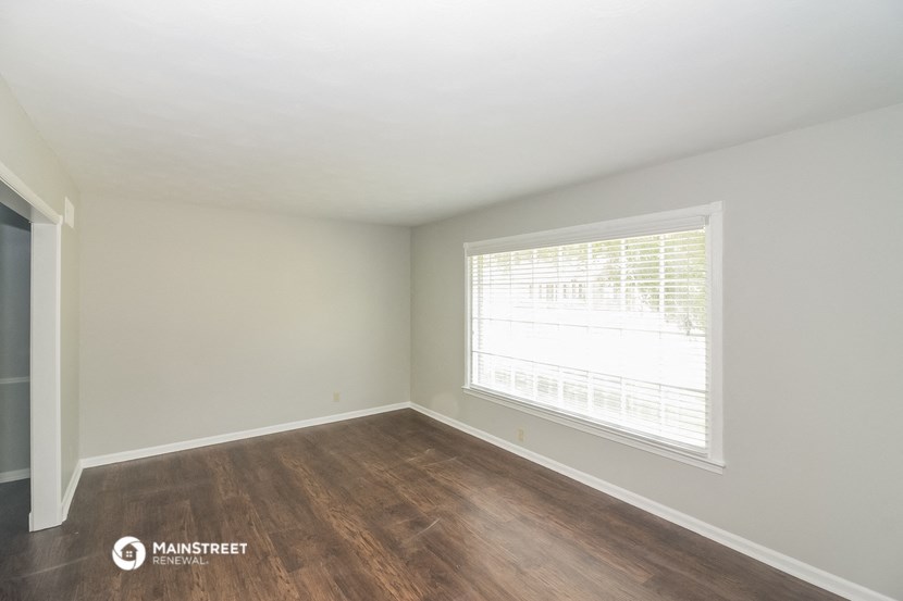 a bedroom with a large window and wood flooring