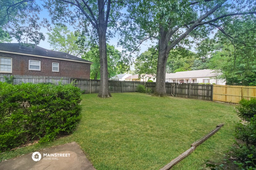 a fenced in backyard with trees and a fence
