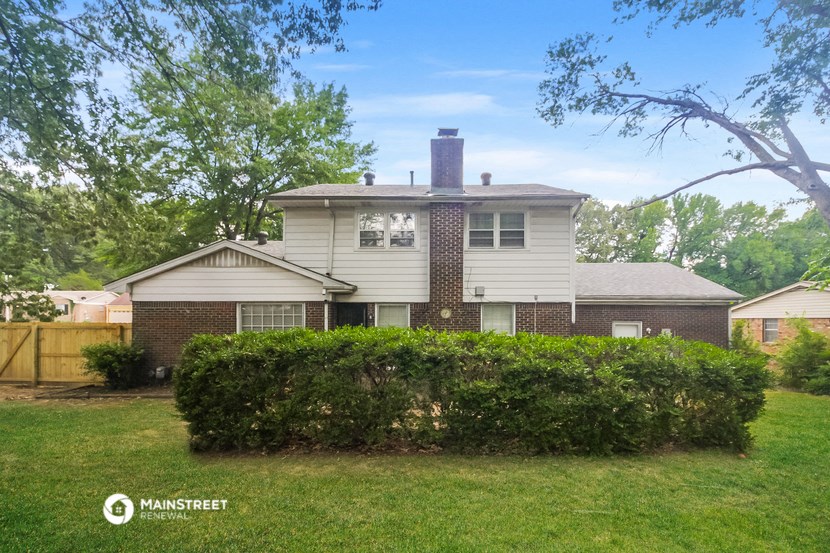 a white and brick house with a yard and a fence