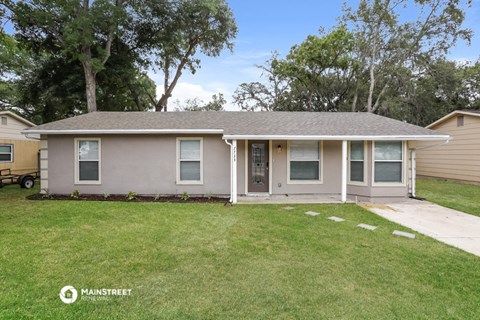 the front of a house with a lawn and trees