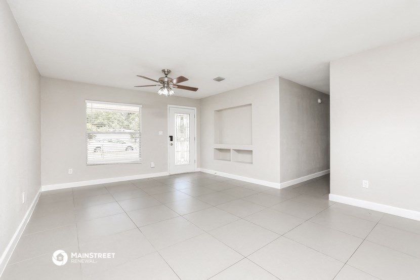 an empty living room with a ceiling fan