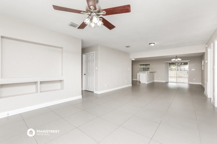 a large empty living room with a ceiling fan